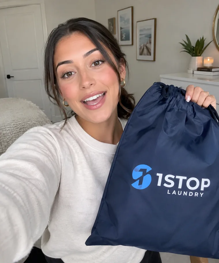 1Stop brand partner holding a navy 1Stop Laundry drawstring bag