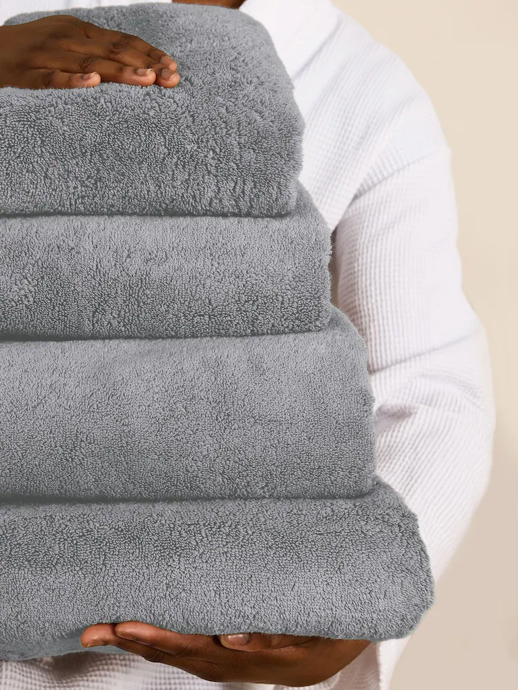 Person's hands hold a stack of folded gray towels